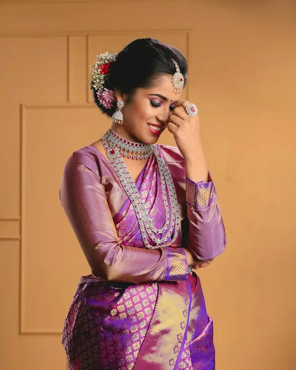 ఊదా, బంగారు రంగు కంచి పట్టు చీర కట్టుకున్న మహిళ